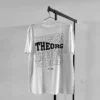 Weißes T-Shirt auf an einem Kleiderbügel an einer Kleiderstange. Der Rückendruck ist viermal THEORG in einer wellenförmigen Schrift untereinander. Das zweite THEORG von oben ist weiß ausgefüllt, die anderen haben eine weißen Konturlinie. Darunter steht est. 1989.